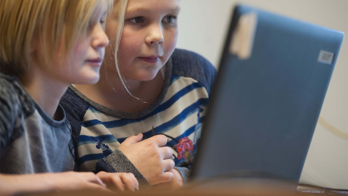 Twee leerlingen kijken naar het beeldscherm van een laptop