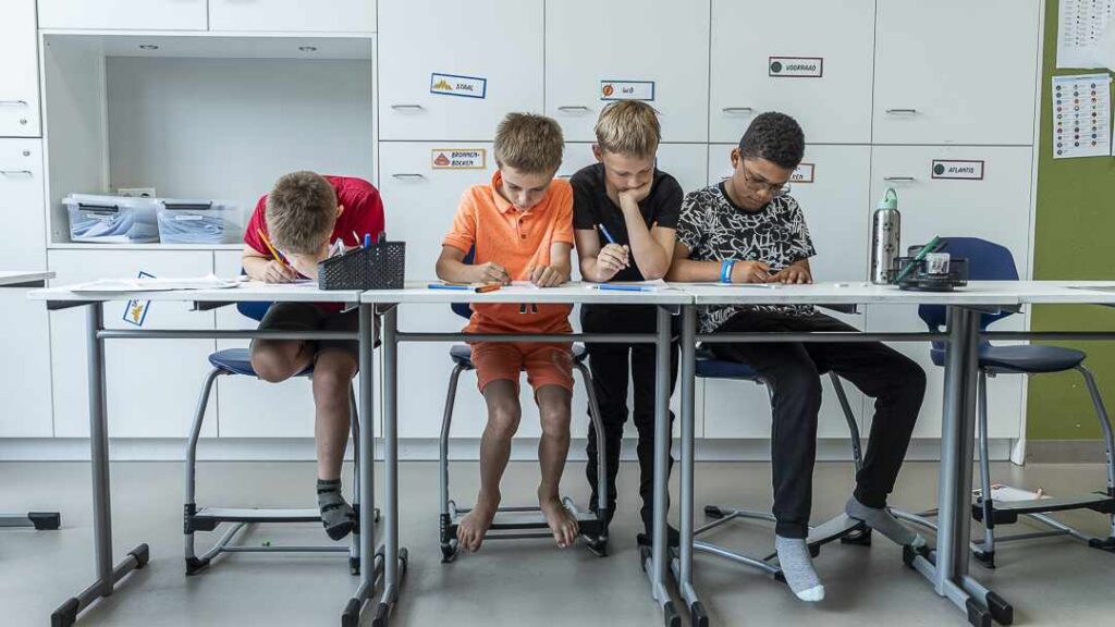 vier jongens werken in de klas in hun schrift