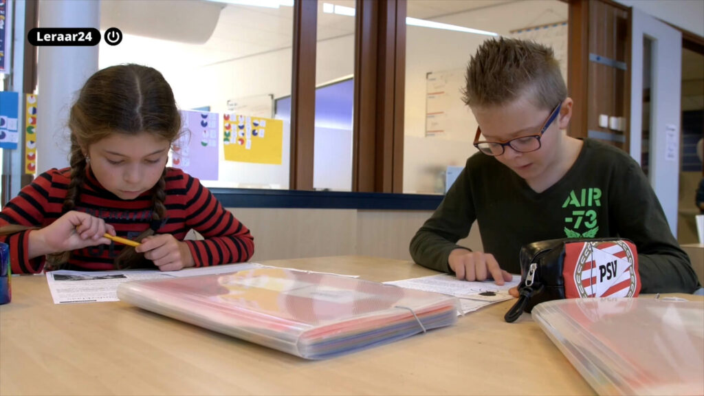 Twee kinderen lezen een tekst in de klas