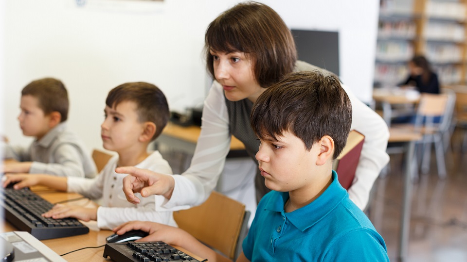 Leraar legt aan leerling uit hoe een computer werkt