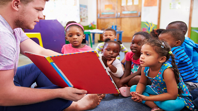 Een leerkracht leest voor aan een klein groepje kinderen.