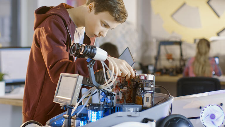 Jongen werkt aan een robot voor een robotica-project op school