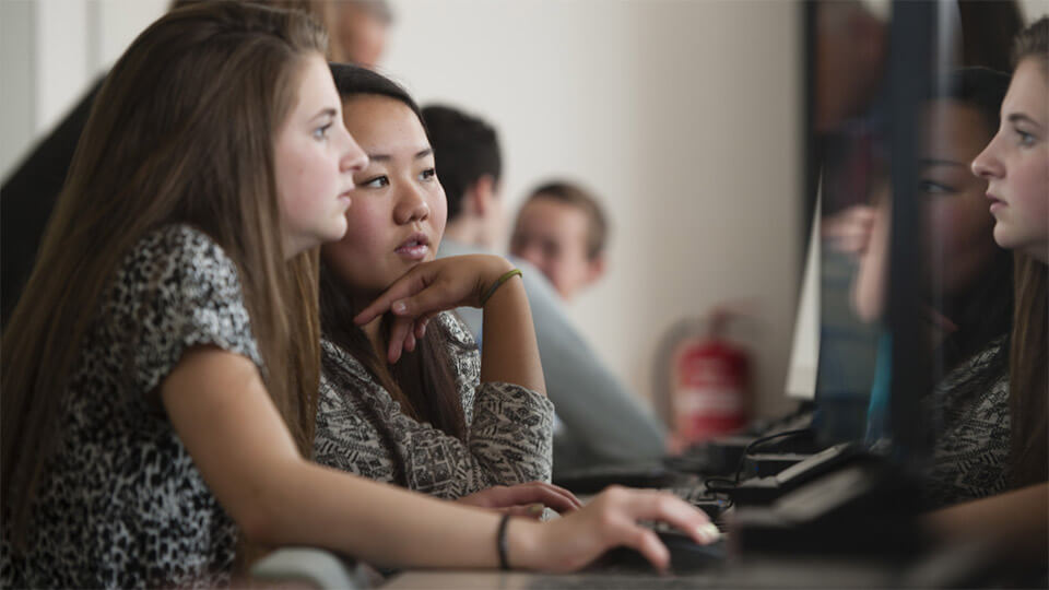 Twee leerlingen zitten achter een computerscherm