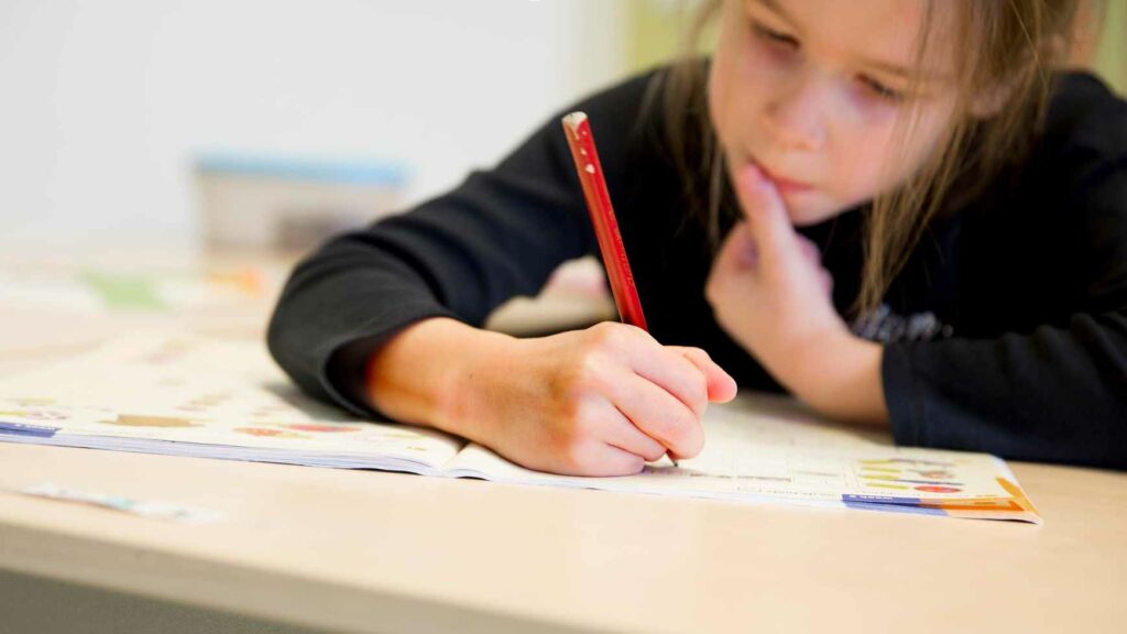 Een basisschoolleerling schrijft in haar schrift