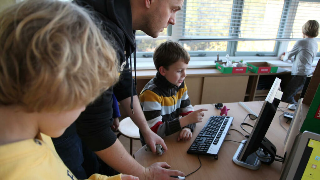 Leraar met leerling achter computer