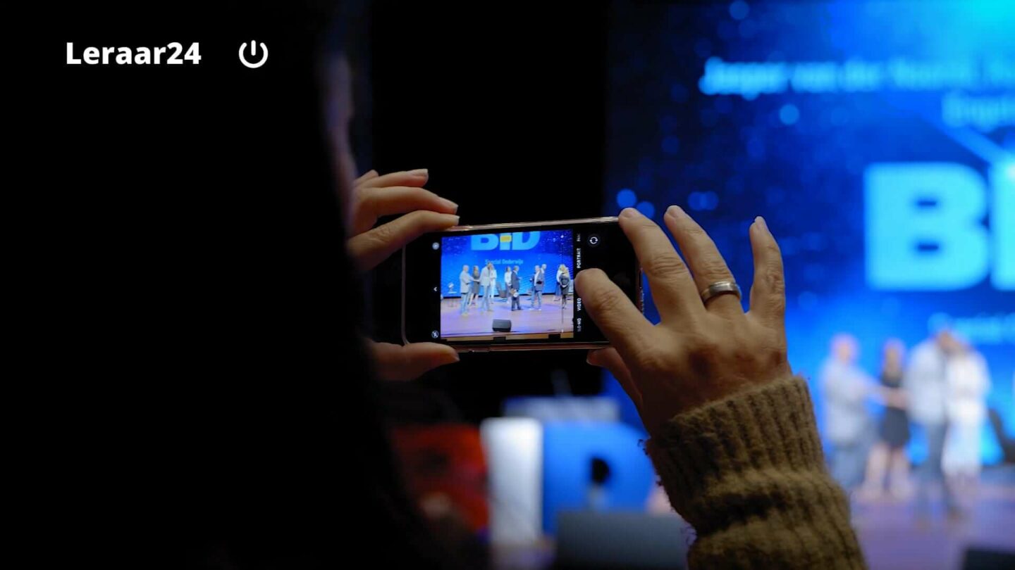 Vrouw maakt foto met smartphone van leraren van het jaar 2021 op het podium
