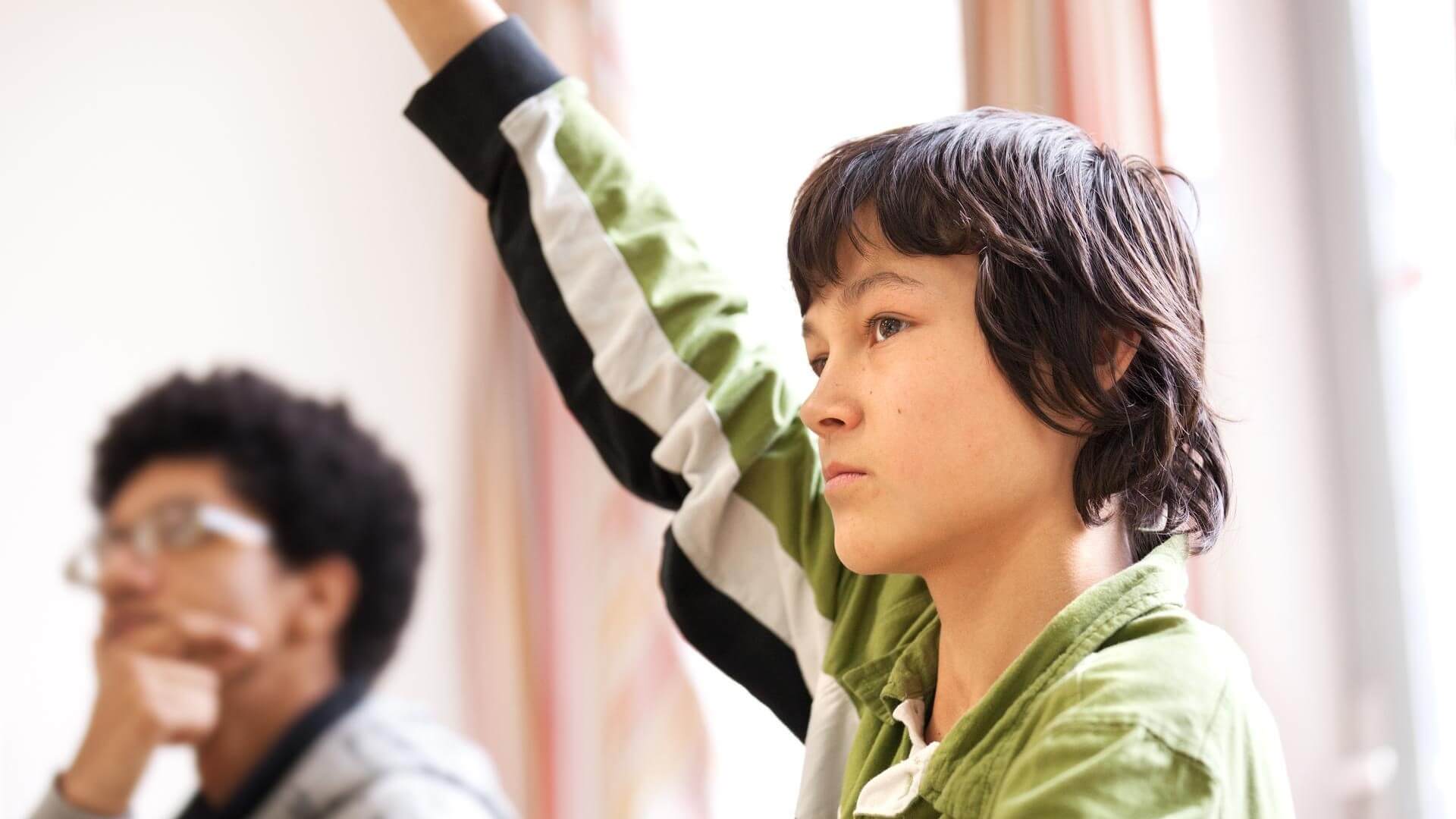 Een jongen steekt zijn vinger op in de klas