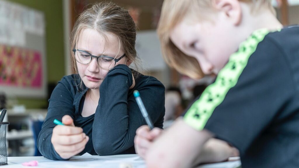 Een jongen en meisje lezen met een pen in de hand