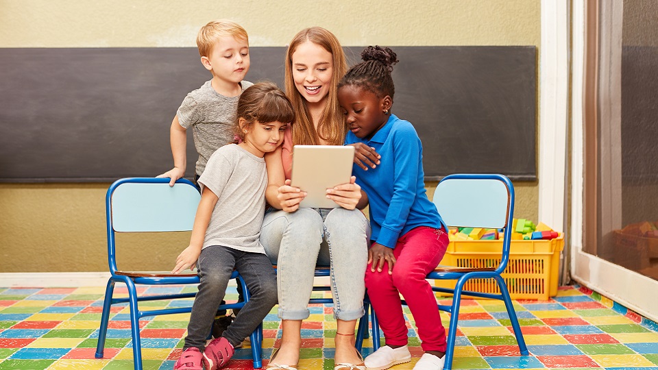 Leraar leest voor van een tablet aan haar leerlingen.