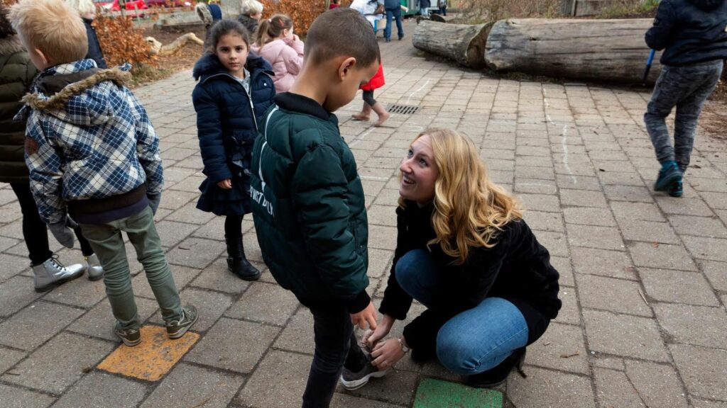 Juf strikt schoen van leerling op het schoolplein