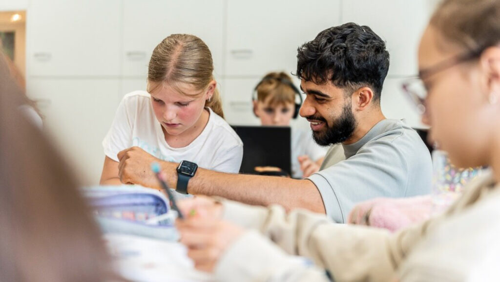 In de klas geeft een leraar een leerling uitleg