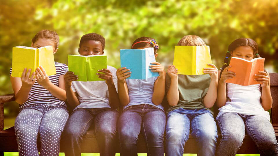 Kinderen zitten op een bankje en houden een boek voor.