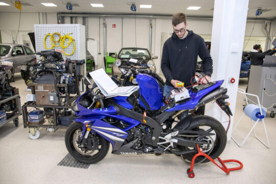 Student leest een blauwe Yamaha-motorfiets uit