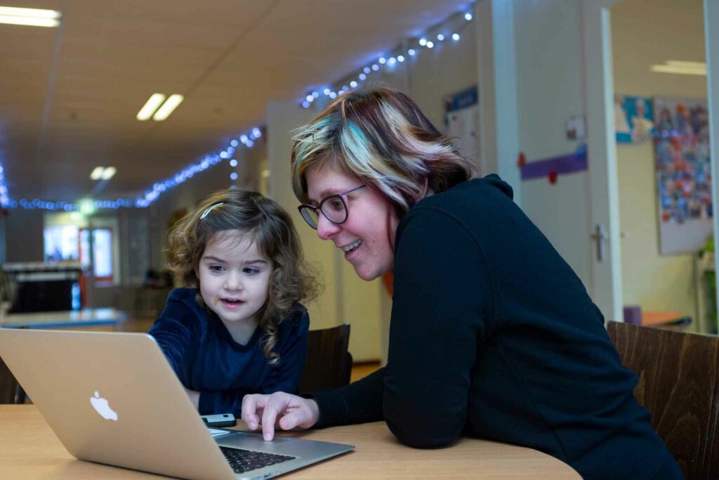 Kleuterjuf en leerling achter een laptop